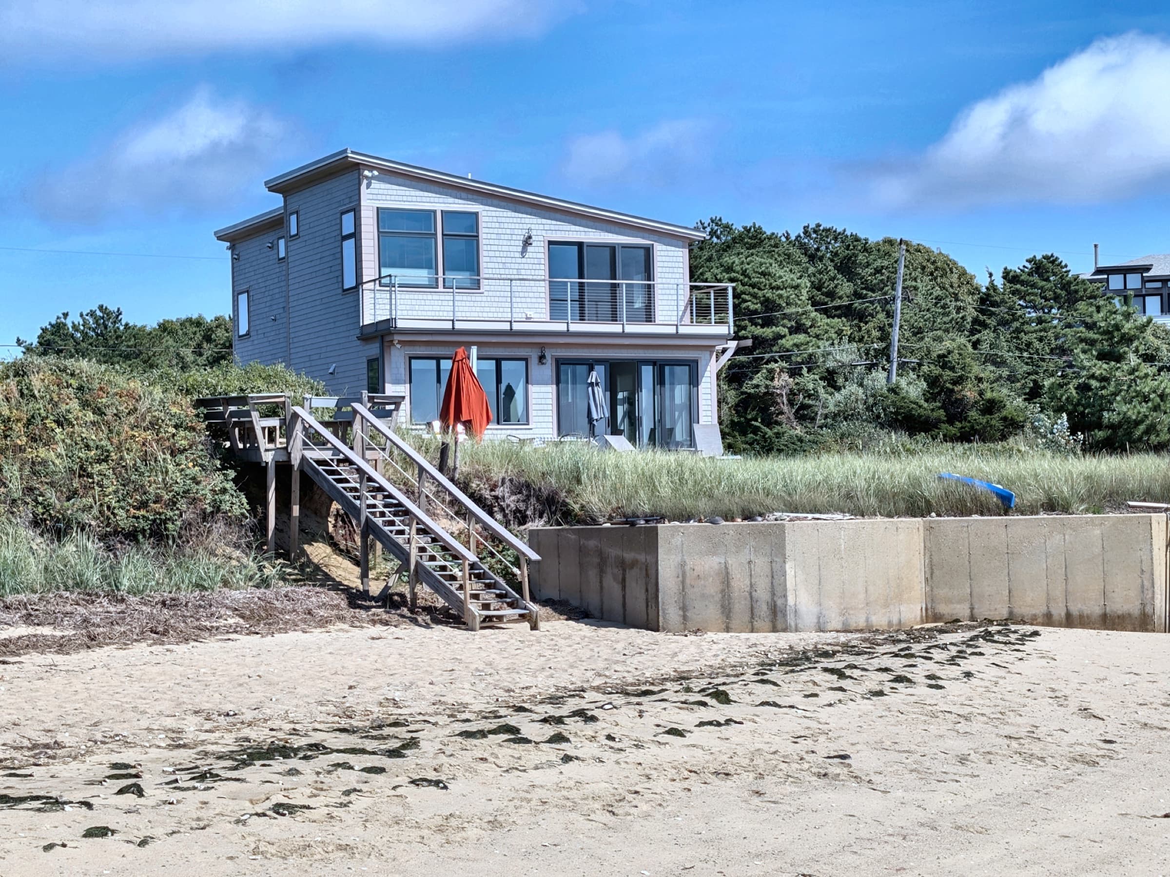 The beach elevation: triple-pane glazing throughout, a nine-foot French door to the second-floor deck heavy enough to need a forklift to set, and a standing-seam metal roof.